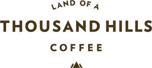 Logo for "Thousand Hills Coffee" featuring bold, stylized text with a rustic, textured appearance.